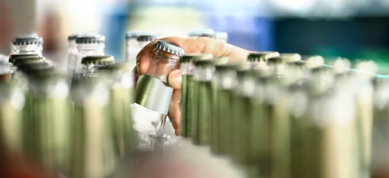 Close-up of someone removing a bottle from rows of glass bottles