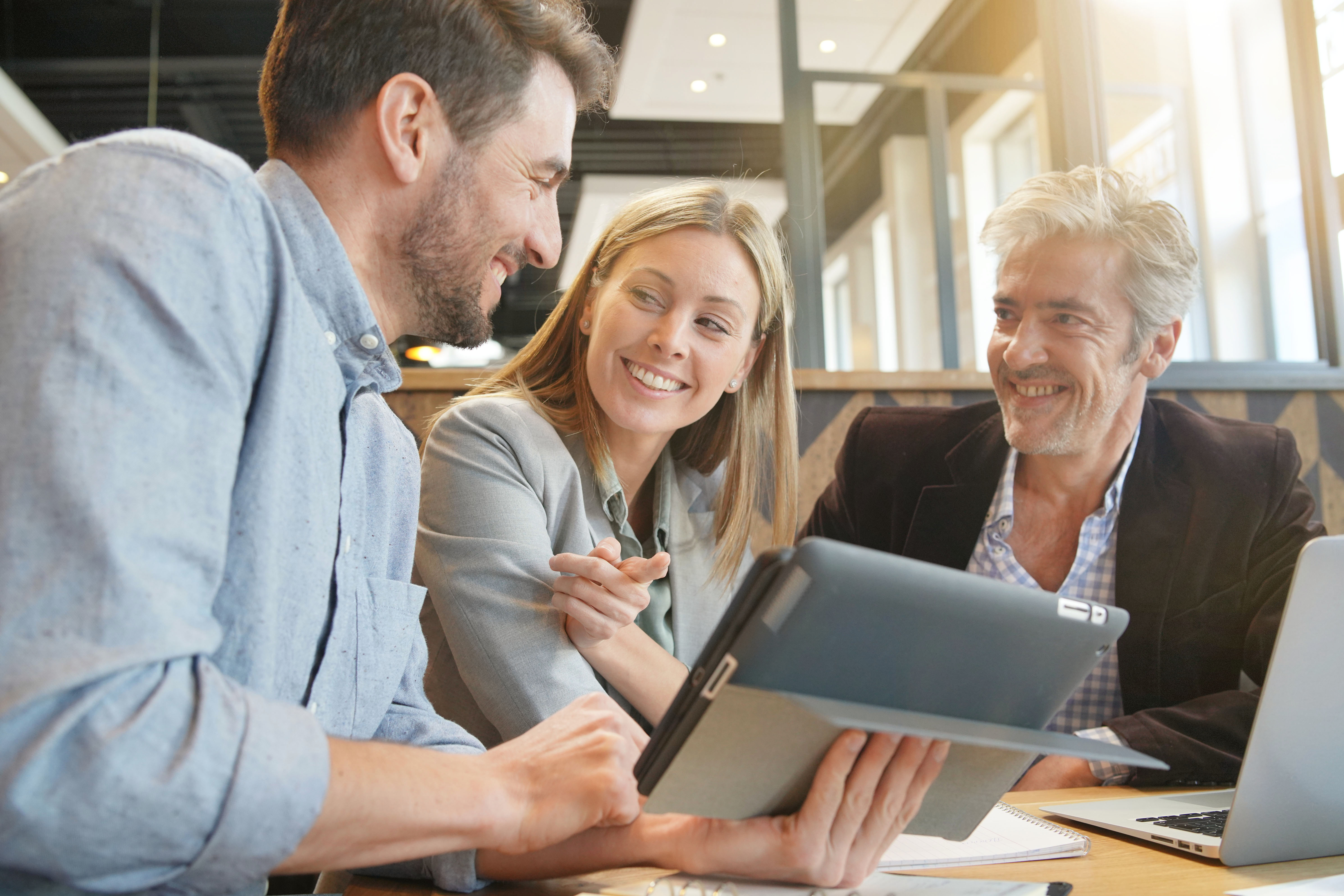 Happy sales team reviewing information on a tablet