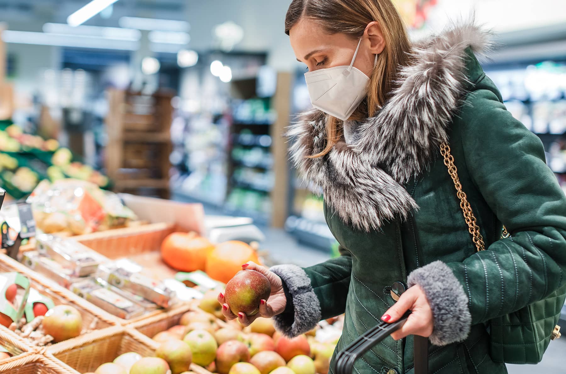 Masked shopper browsing the fresh fruit aisle of a supermarket