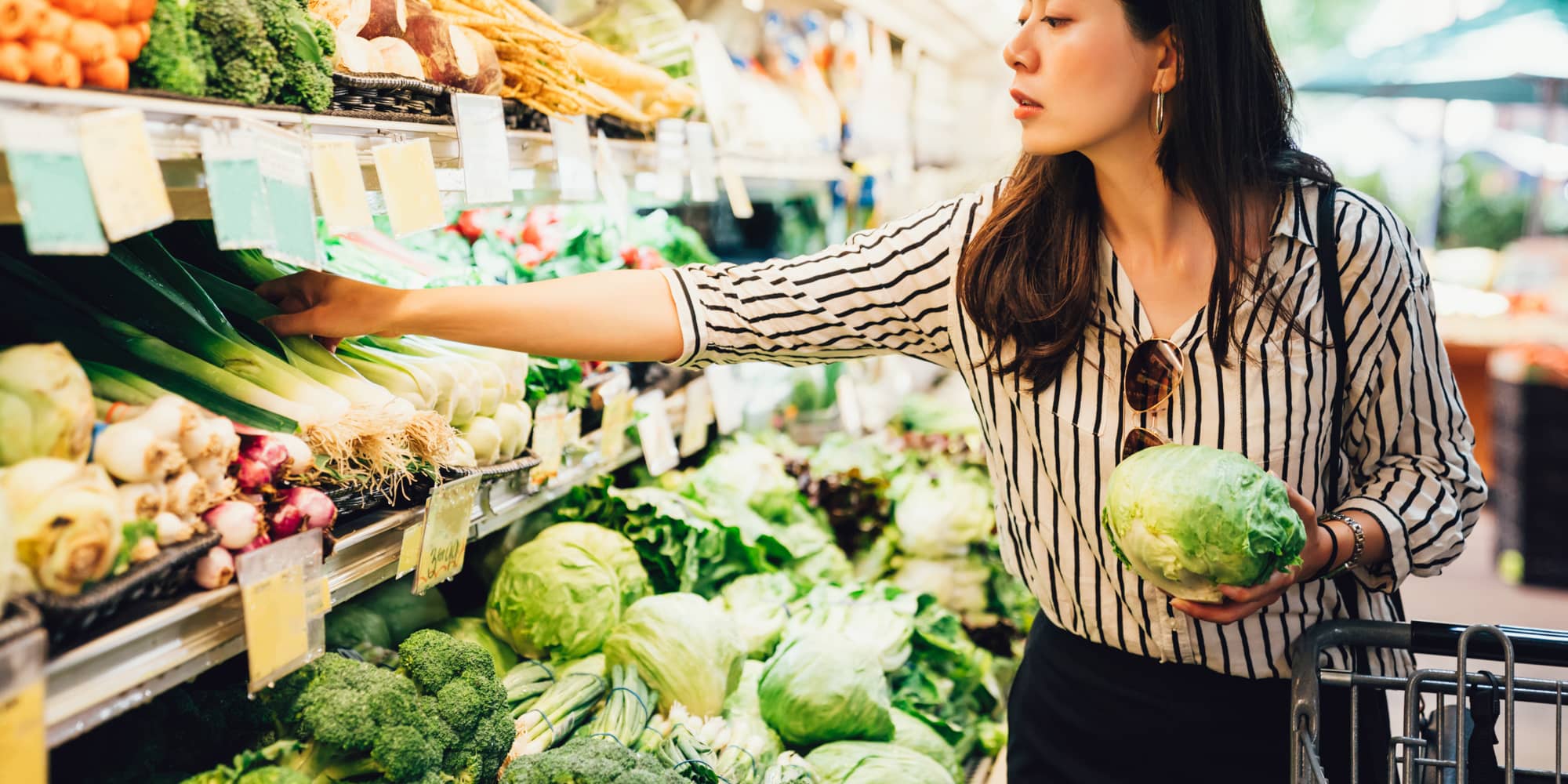 Woman choosing fresh vegetables at grocery retailer