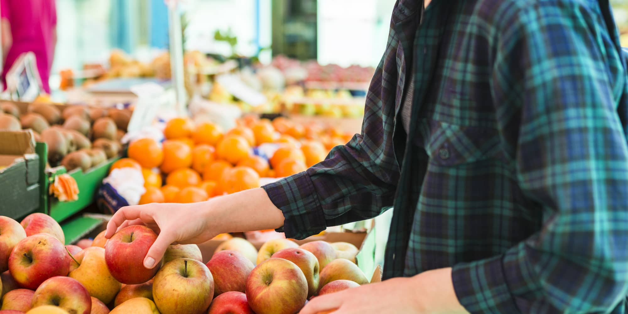 Person picking up an apple at a grocery retailer 